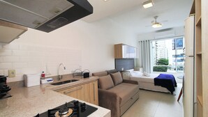 A compact kitchen with a gas stove, a sink, and a window overlooking a balcony. - Rio Spot Homes C056 (Rio de Janeiro)