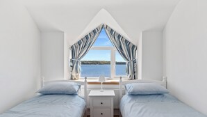 Un dormitorio con dos camas, una mesita de noche y una ventana con cortinas.