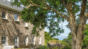 A stone building with multiple windows and a white picket fence. - Druidston Old Farmhouse (Druidston Haven)