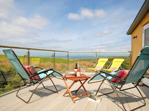 Ein Balkon mit zwei Loungestühlen, einem Tisch mit Flasche und Gläsern und Blick auf die Landschaft.