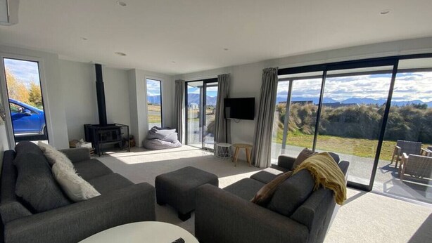 A modern living room with a large TV, grey sofas, a white coffee table, and a fireplace.