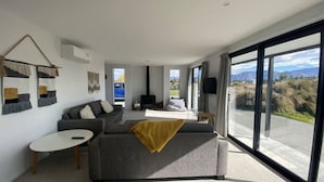 A modern living room with a sofa, a small table, and a large window offering a view of the outdoors.