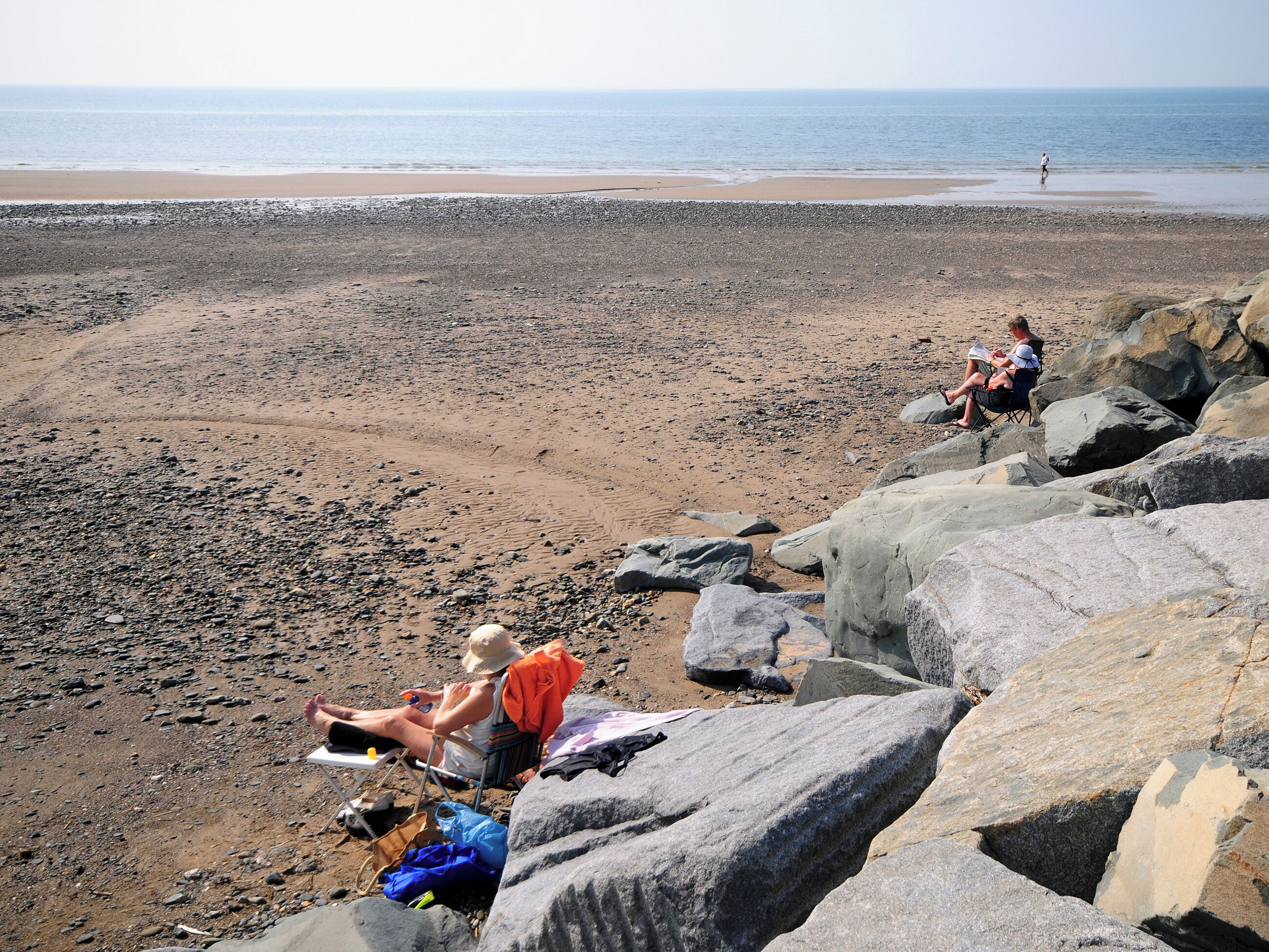 A rocky beach with large boulders and a sandy shore.