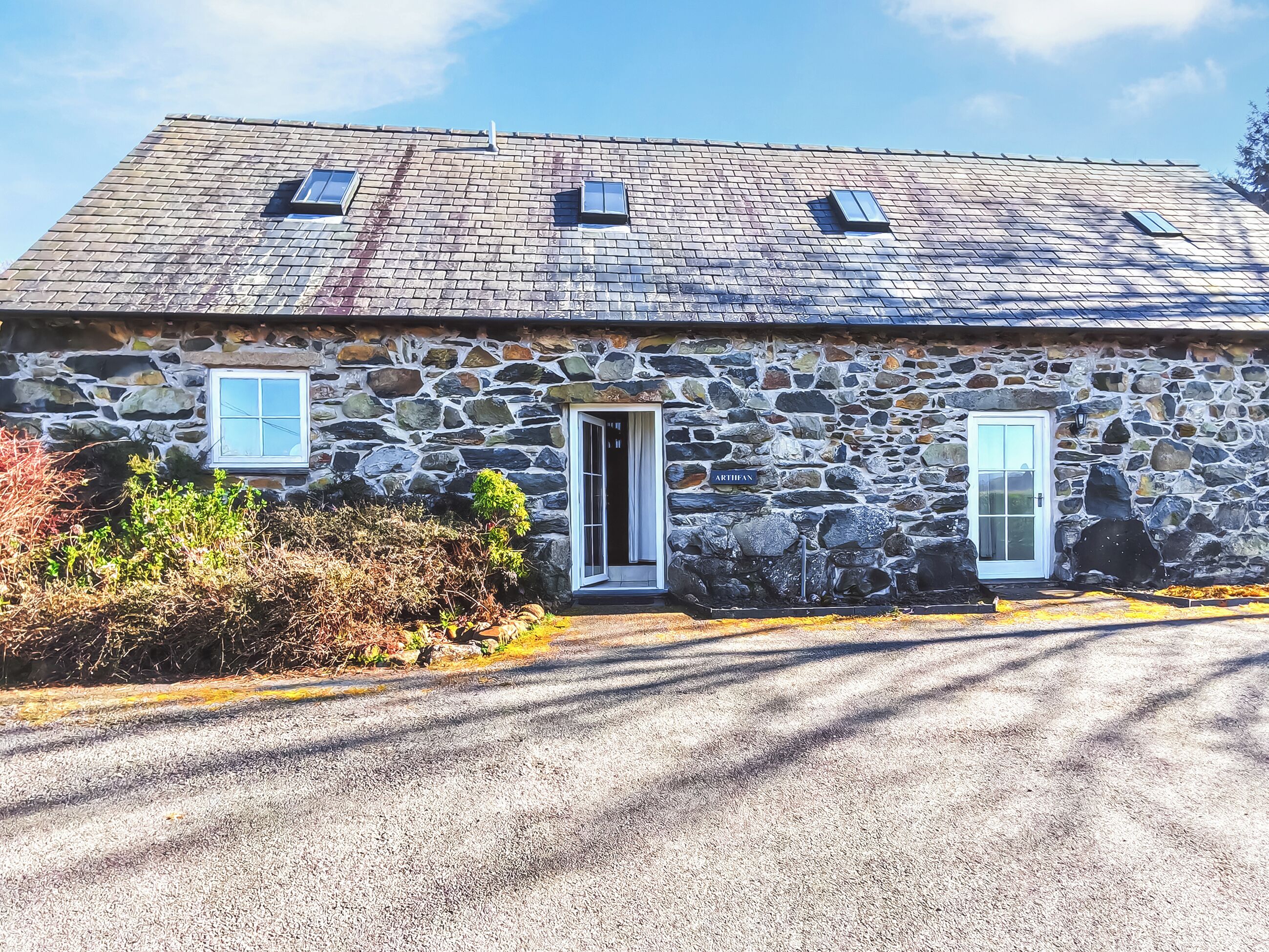 Un bâtiment en pierre avec un toit en pente, deux fenêtres et une porte.