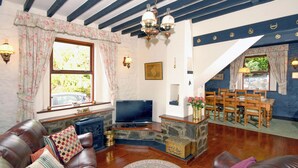 Una sala de estar con chimenea de piedra, sofá de cuero, mesa de comedor de madera y televisor.