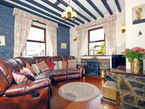 A living room with a leather sofa, a stone fireplace, and a chandelier.