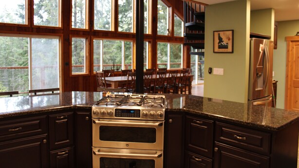Una cocina con un horno empotrado grande, armarios de madera y vistas al exterior a través de amplias ventanas.