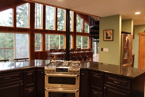 Una cocina con un horno empotrado grande, armarios de madera y vistas al exterior a través de amplias ventanas.