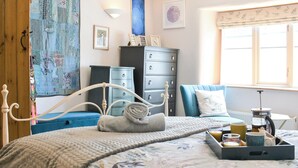 Quarto com cama, cômoda e janela com cortinas.