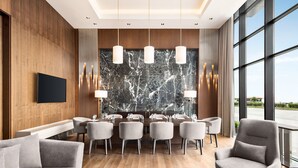 A modern hotel lobby with a marble wall, a dining area with a long table and chairs, and a large window offering a view of the outdoors. - Ramada by Wyndham Rize Findikli (Findikli)