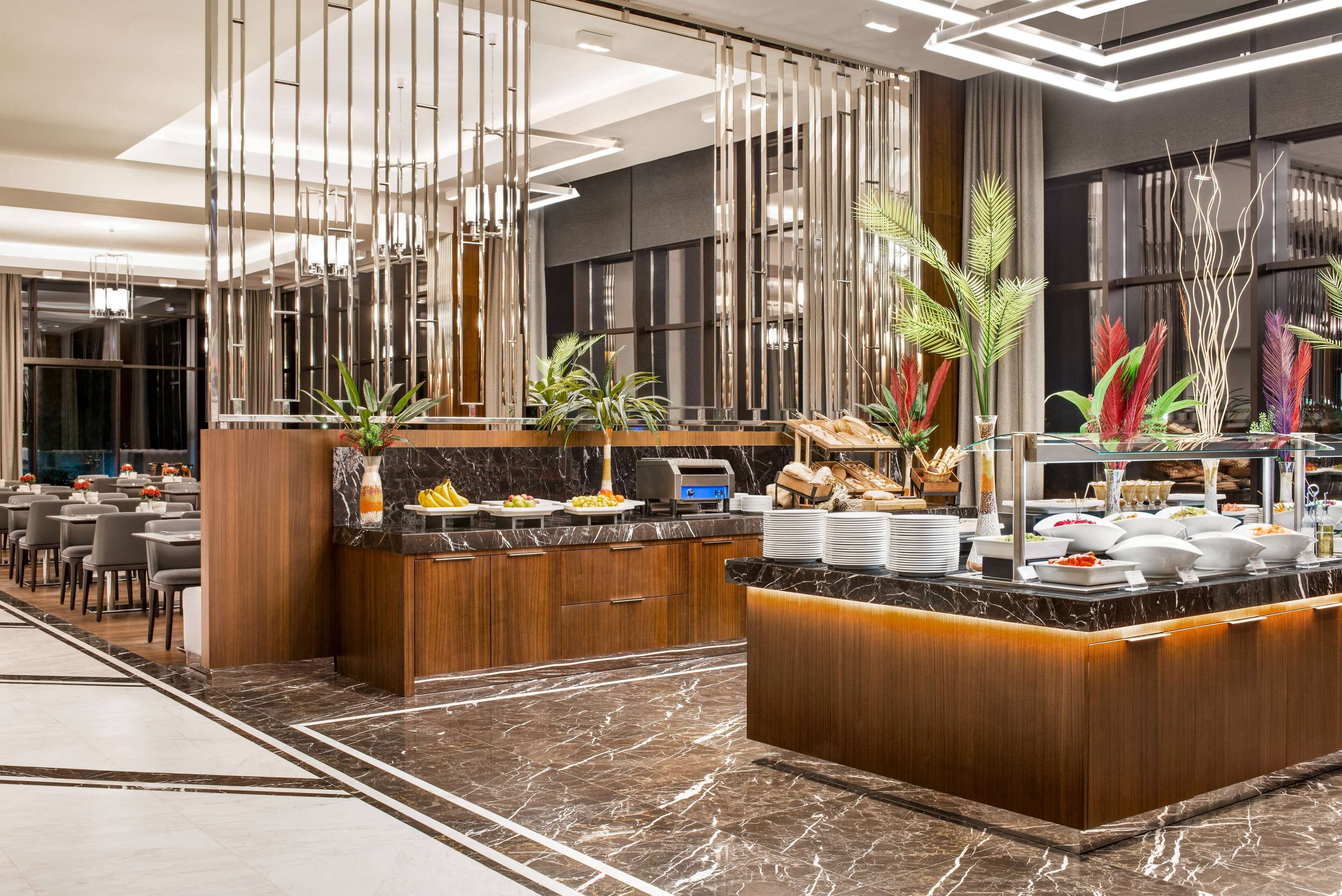 Un hall d’hôtel moderne avec un comptoir d’accueil en marbre, un espace salon et un buffet.