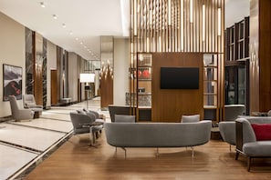 Un hall d’entrée moderne doté de sièges, d’un téléviseur à écran plat et d’un mur revêtu de panneaux en bois.