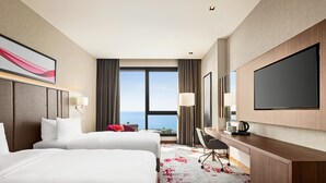 A hotel room with two beds, a desk, a chair, a flat-screen TV, and a view of the sea. - Ramada by Wyndham Rize Findikli (Findikli)