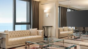 A modern hotel room with a large window, a tufted sofa, a glass coffee table, and a large mirror. - Ramada by Wyndham Rize Findikli (Findikli)
