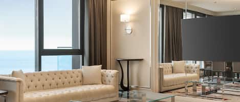 Een moderne hotelkamer met een groot raam, een gestoffeerde bank, een glazen bijzettafeltje en een grote spiegel.