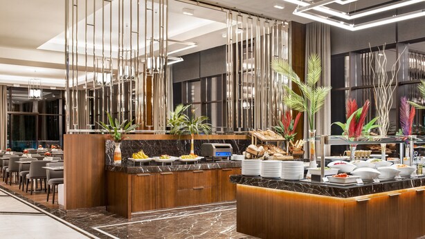 A modern hotel lobby with a marble floor, a reception desk, and a buffet area with various food items. - Ramada by Wyndham Rize Findikli (Findikli)