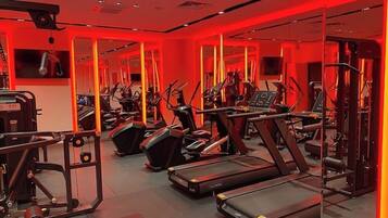 Un gimnasio con cintas de correr, elípticas y equipo de levantamiento de pesas.