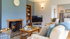 A cozy living room with a fireplace, a television, and a bookshelf.