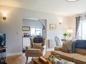 A living room with a sofa, armchair, and a coffee table with a teapot. - 1 bedroom accommodation in Richards Castle, near Ludlow (Richards Castle, near Ludlow)