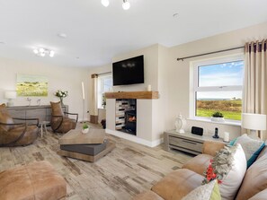A living room with a fireplace, a television, and a view of the outdoors.