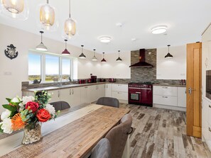 Una cocina moderna con una mesa de comedor de madera, luces colgantes y vistas al exterior.