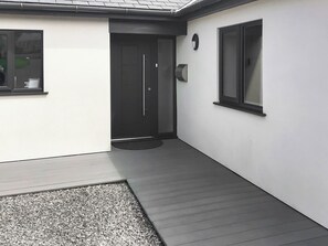 Un edificio moderno con una puerta negra, una ventana pequeña y un felpudo.