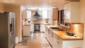 A modern kitchen with stainless steel appliances, wooden countertops, and a central island.