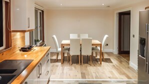 A modern kitchen with a wooden countertop, a dining table with chairs, and a patterned floor.