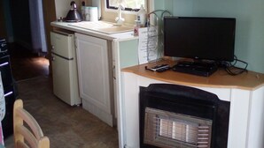 A compact kitchen with a refrigerator, a sink, a stove, a microwave, a television, and a small heater. - River Views Dog Friendly Caravan 3 Bedrooms (Rye)