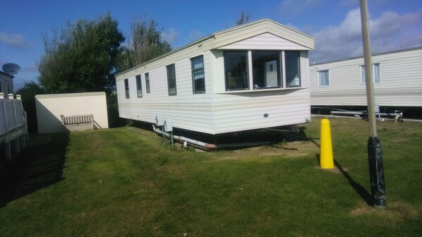 A mobile home with a front porch, a satellite dish, and a small attached garage. - River Views Dog Friendly Caravan 3 Bedrooms (Rye)