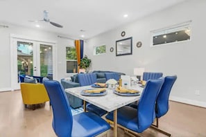 A dining area with a marble table, blue chairs, and a yellow chair.