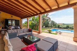 A covered patio with wicker furniture, a pool, and a view of the surrounding landscape. - Canvu, Finca 5StarsHome Mallorca (Ses Salines)