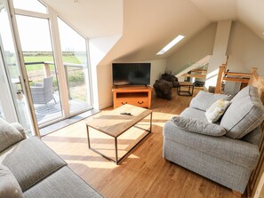 A spacious living area with a sofa, a coffee table, and a television. - Glowty Brynbedw (Clynderwen)