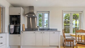 A modern kitchen with white cabinetry, a built-in oven, and a stainless steel range hood. - Rogeston House is a stunning and unusual annexe added to the original house. (Johnston, near Haverfordwest)