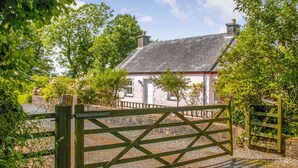 A white house with a grey roof, surrounded by greenery and a wooden gate. - 2 bedroom accommodation in Landshipping, near Narberth (Landshipping, near Narberth)