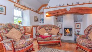 A cozy living room with floral-patterned armchairs, a wooden coffee table, and a fireplace. - 2 bedroom accommodation in Landshipping, near Narberth (Landshipping, near Narberth)