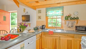 A kitchen with wooden cabinets, a dishwasher, a microwave, and a window with a view of greenery. - 2 bedroom accommodation in Landshipping, near Narberth (Landshipping, near Narberth)