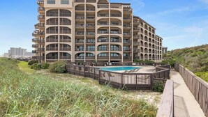 A multi-story hotel with a pool area, surrounded by a wooden deck and a boardwalk. - Waterfront *Extended Stay Discount* Pet Friendly (Myrtle Beach)