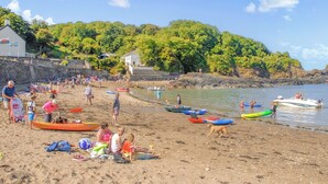 A beach with people, boats, and a dog. - Wisteria Lodge - QC1677 (Preseli Hills)