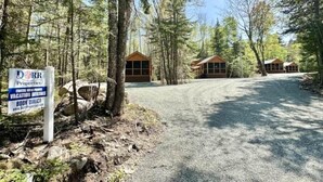 A gravel driveway leading to a cabin-style vacation rental with a sign advertising direct booking. - Cozy Coastal Cabin #3 (Steuben)