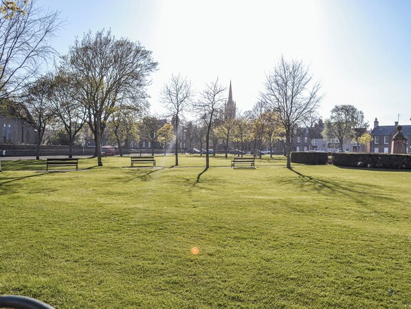 Un parco con panchine e la guglia di una chiesa in lontananza.