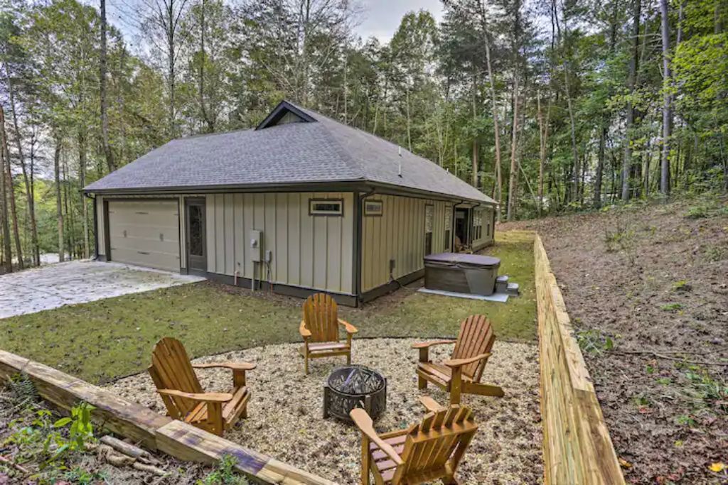 A cabin with a fire pit and Adirondack chairs in the yard.
