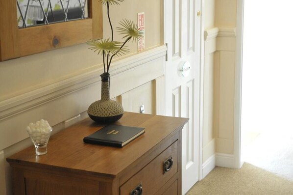A wooden desk with a vase, a bowl of candies, and a book.