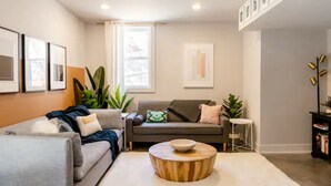 A modern living room with a grey sofa, a round coffee table, and a bookshelf. - Unique & Stylish Private East Atlanta Getaway (Atlanta)