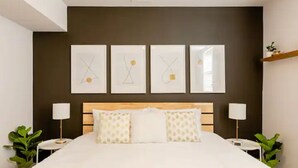 A hotel room with a large bed, two bedside tables, a headboard, and four framed artworks on the wall. - Unique & Stylish Private East Atlanta Getaway (Atlanta)