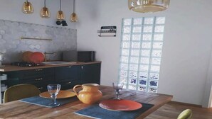 Un comedor con mesa de madera, sillas y una cocina al fondo.