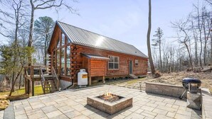 Eine Blockhütte mit Feuerstelle und Grillplatz im Freien.
