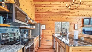 Eine moderne Küche mit Holzwänden und einer zentralen Kochinsel, ausgestattet mit Edelstahlgeräten und Granit-Arbeitsplatten.