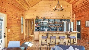 Ein Holzhütten-Interieur mit einer Küche, Barhocker und einer Couch.