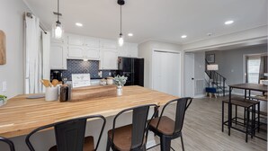 A modern kitchen with white cabinets, a wooden island, and pendant lighting.